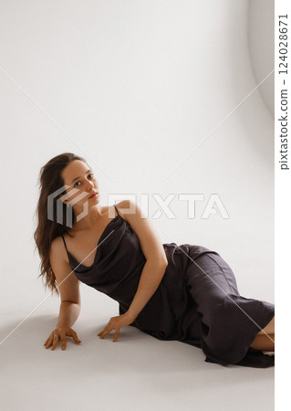 Elegant Woman in a Dark Slip Dress Posing on a White Background 124028671
