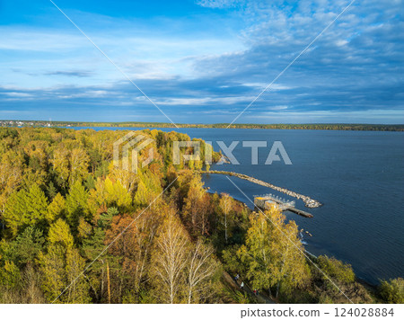 Autumn forest on lake shore at sunset and city on horizon, auerial view 124028884