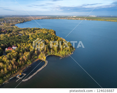 Autumn forest on lake shore at sunset and city on horizon, auerial view 124028887