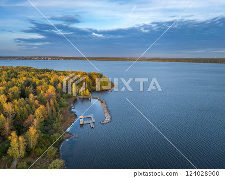 Autumn forest on lake shore at sunset and city on horizon, auerial view 124028900