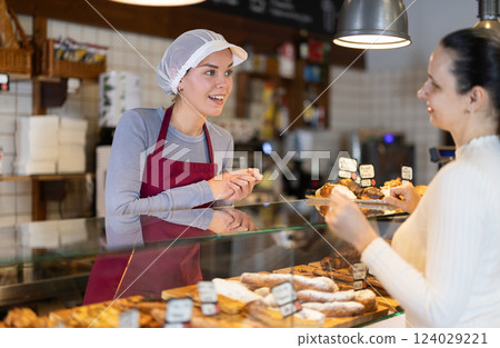 Saleswoman offers bakery customers to buy fresh baked goods Saleswoman offers bakery customers to buy fresh baked goods 124029221