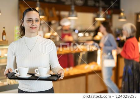 Breakfast in cafe - woman carries tray with two cups of coffee 124029253
