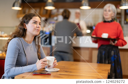 Girl whiles away time and waits for meeting in chain cafe 124029272