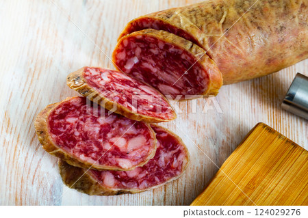 Spanish salchichon sausage cut in slices on a wooden surface 124029276