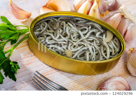 Open tin can of pickled eels and garlic with greens at table Open tin can of pickled eels and garlic with greens at table 124029296