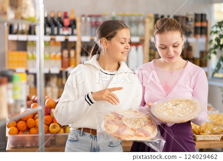 Young women choosing pizza in grocery store Young women choosing pizza in grocery store 124029462