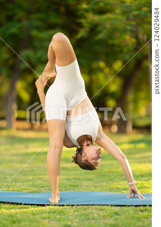 Young woman practicing yoga on green glade in summer park 124029484