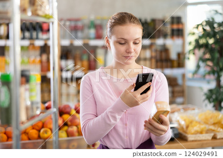 Female buyer scans QR code on cheese label in grocery store 124029491