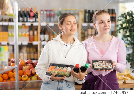 Young women choose sushi and sauces for them Young women choose sushi and sauces for them 124029521