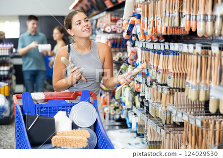 Woman choose brush made for painting wooden surfaces and selects desired option 124029530