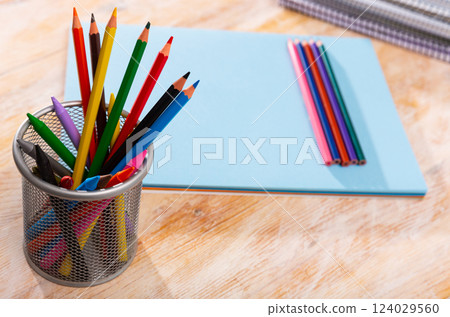 Multicolored pencils and papers on wooden background 124029560