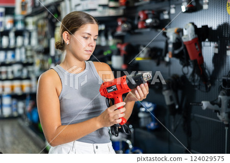 Woman buys electric drill, collect necessary supplies in store according to list for apartment repairs 124029575