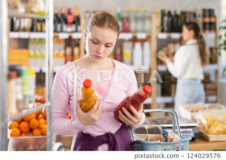 woman chooses juices against the background of buyers woman chooses juices against the background of buyers 124029576