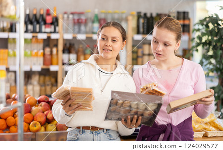 Two women choose sweets in supermarket Two women choose sweets in supermarket 124029577