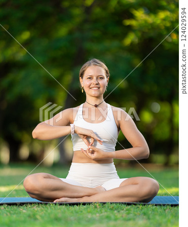 Girl meditating in lotus position during yoga session in summer park 124029594