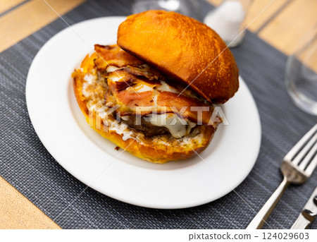 Cheeseburger with beef patty and fried bacon slices in bun 124029603