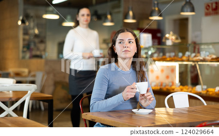 Portrait of girl with cup in hands drinking coffee in coffee shop indoors 124029664