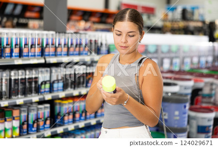 Young female customer buying spray paint can in supermarket Young female customer buying spray paint can in supermarket 124029671