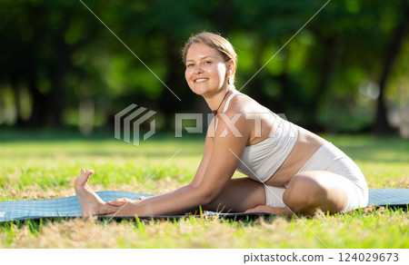 Girl enjoying outdoor yoga practice in green summer park Girl enjoying outdoor yoga practice in green summer park 124029673