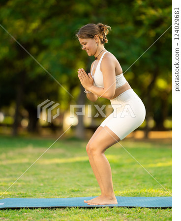 Young woman practicing yoga on green glade in summer park 124029681
