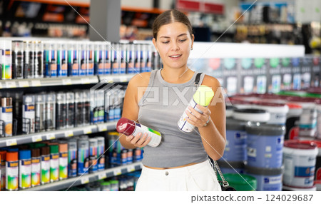Young female customer buying spray paint can in supermarket Young female customer buying spray paint can in supermarket 124029687