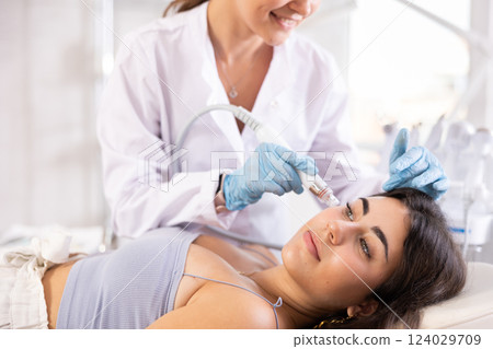 Young girl receiving facial procedure with hydrogen and oxygen ions attachment Young girl receiving facial procedure with hydrogen and oxygen ions attachment 124029709