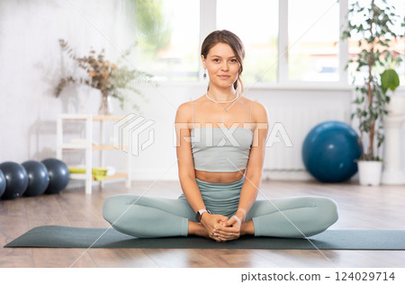 Slender athletic young woman doing stretching and taking various yoga poses in gym 124029714