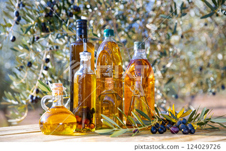 Bottles with olive oil and olive branch on a wooden table Bottles with olive oil and olive branch on a wooden table 124029726