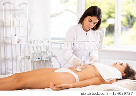 Female doctor making belly beauty massage with vibration attachement Female doctor making belly beauty massage with vibration attachement 124029727