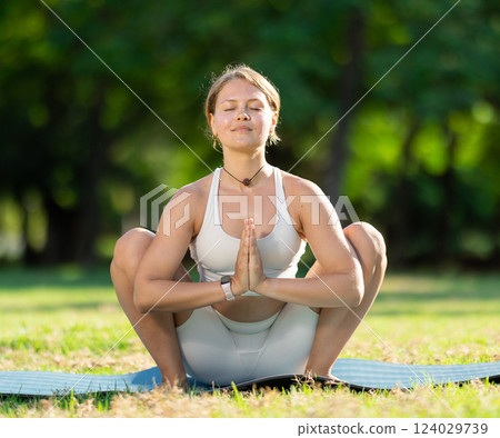 Sporty girl performing yoga asanas on green meadow in summer Sporty girl performing yoga asanas on green meadow in summer 124029739