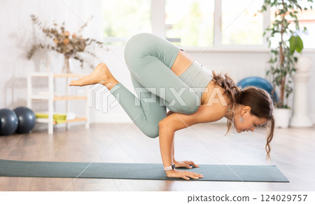 Experienced girl fitness club teacher performs shadoof asana, bakasana Experienced girl fitness club teacher performs shadoof asana, bakasana 124029757