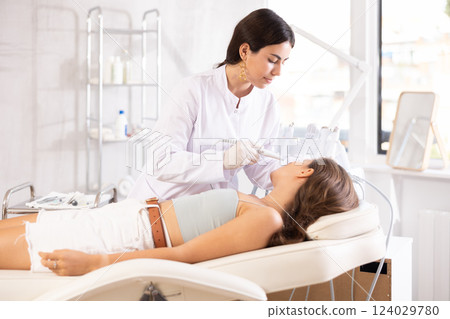 female doctor making facial beauty procedure with leather knife attachment 124029780
