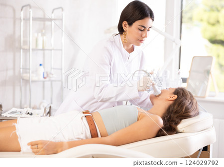 Female aesthetician administering high frequency ultrasound facial procedure on woman 124029792