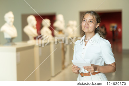 Woman with sheet piece of paper in hands view sculpture in museum hall Woman with sheet piece of paper in hands view sculpture in museum hall 124029870