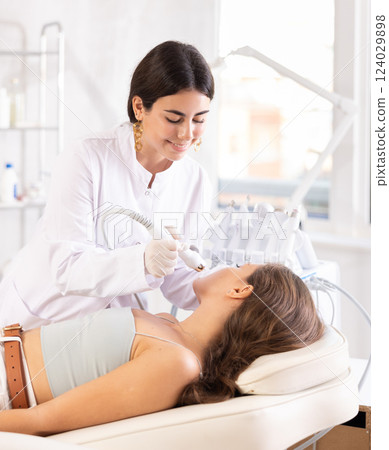 Female doctor making facial beauty procedure with macro molecule atomizing pen Female doctor making facial beauty procedure with macro molecule atomizing pen 124029898