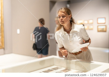 Girl looks at various paintings and drawings at an art exhibition in museum 124029937