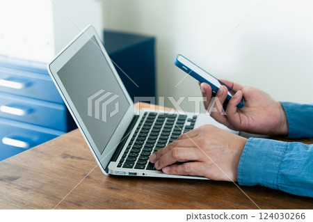一名男子操作智慧型手機和電腦 一名男子操作智慧型手機和電腦 124030266