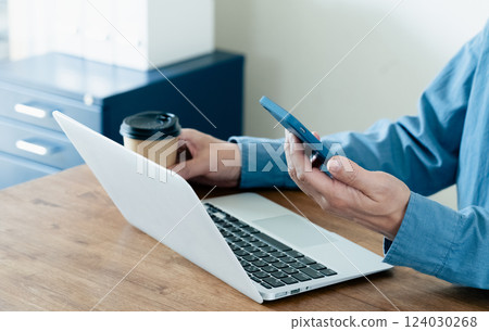 A man operating a smartphone and a computer A man operating a smartphone and a computer 124030268