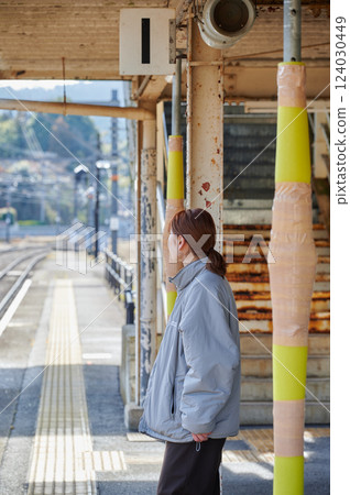 A woman waiting for a train at the station home 124030449