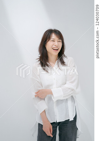 Middle-aged woman standing in front of a white wall 124030709