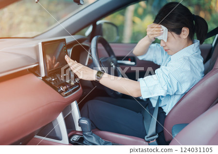 woman driving car with broken air conditioner in hot summer weather, uses tissue paper napkin to wipe the sweat off her forehead. Businesswoman driver is tired, Exhausted overheated and stressed 124031105