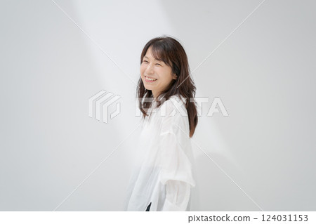 Middle-aged woman standing in front of a white wall Middle-aged woman standing in front of a white wall 124031153