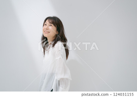 Middle-aged woman standing in front of a white wall Middle-aged woman standing in front of a white wall 124031155