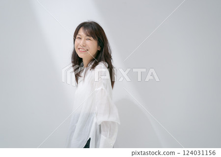 Middle-aged woman standing in front of a white wall Middle-aged woman standing in front of a white wall 124031156