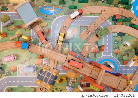 Colorful wooden train set with vehicles on a vibrant play mat depicting roads and nature, encouraging imaginative play in kids during afternoon hours Colorful wooden train set with vehicles on a vibrant play mat depicting roads and nature, encouraging imaginative play in kids during afternoon hours 124032201