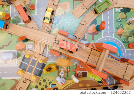 Colorful wooden train set with vehicles on a vibrant play mat depicting roads and nature, encouraging imaginative play in kids during afternoon hours Colorful wooden train set with vehicles on a vibrant play mat depicting roads and nature, encouraging imaginative play in kids during afternoon hours 124032202