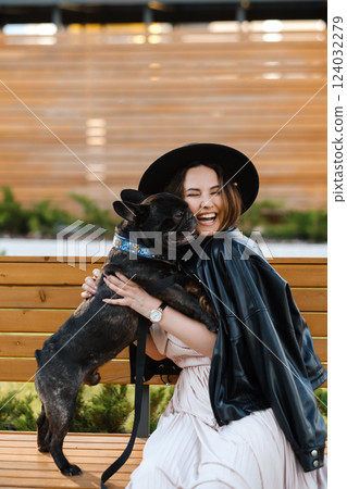 Woman joyfully embraces her French bulldog in a cozy outdoor setting during a sunny day Woman joyfully embraces her French bulldog in a cozy outdoor setting during a sunny day 124032279