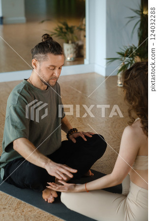 Couple practicing partner yoga in a serene indoor studio during an evening session with warm lighting and calming atmosphere Couple practicing partner yoga in a serene indoor studio during an evening session with warm lighting and calming atmosphere 124032288