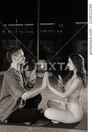 Couple practices synchronized yoga session together in a tranquil studio setting during the early morning hours focusing on mindfulness and connection 124032298