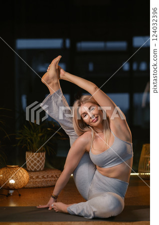 Yoga practitioner demonstrates impressive flexibility in serene studio setting during evening relaxation session with soft lighting Yoga practitioner demonstrates impressive flexibility in serene studio setting during evening relaxation session with soft lighting 124032396